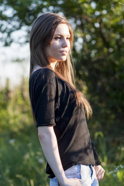 Beautiful girl with long, straight hair posing in the field with sunset light, against the light — Stock Photo, Image