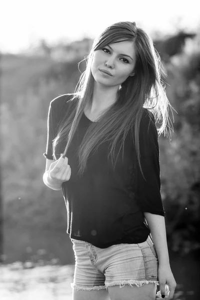 Hermosa chica de pelo largo y liso posando en el campo con luz del atardecer, contra la luz — Foto de Stock