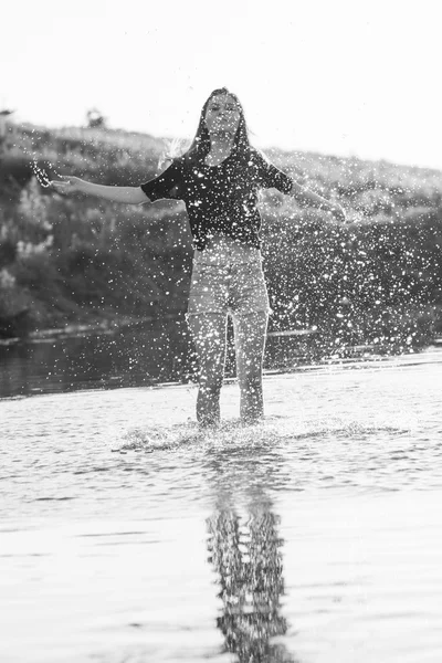 Schöne Mädchen mit langen, glatten Haaren posiert und spielt mit Wasser in einem kleinen Fluss — Stockfoto