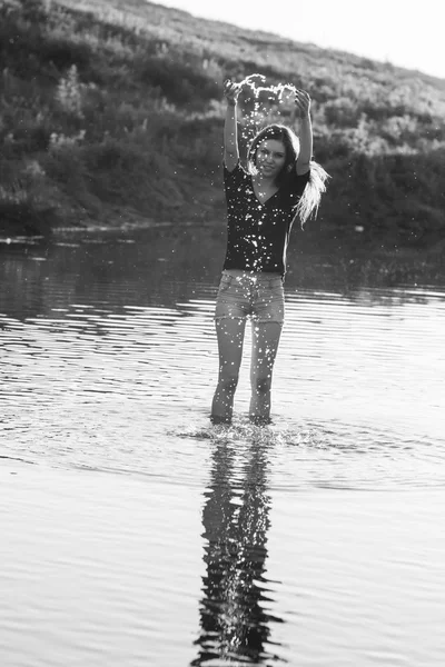 Девочка с длинными прямыми волосами позирует и играет с водой в маленькой реке — стоковое фото