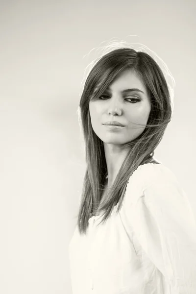 Черно-белое фото красивой кавказской девушки в белой блузке на светло-сером фоне — стоковое фото