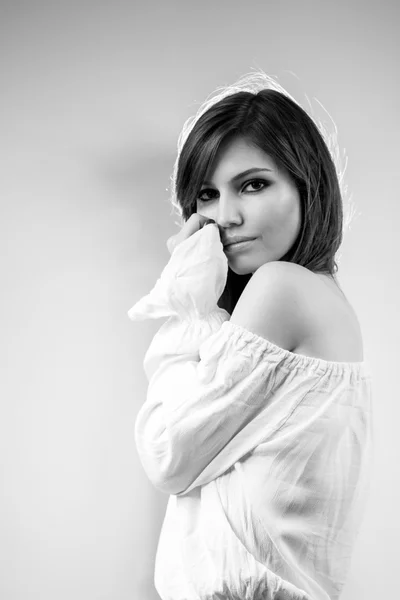 Foto en blanco y negro de una hermosa chica caucásica con una blusa blanca con fondo gris claro — Foto de Stock