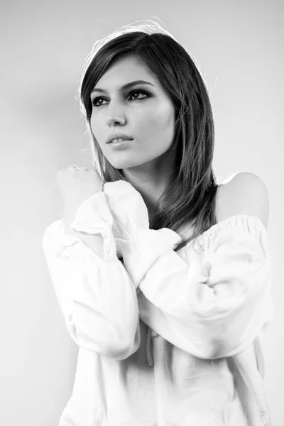Svartvitt foto av vackra kaukasiska flicka klädd i en vit blus med ljus grå bakgrund — Stockfoto