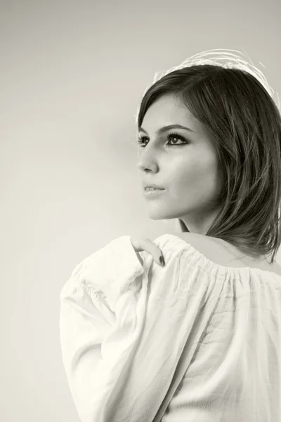 Black and white photo of beautiful caucasian girl wearing a white blouse with light grey background — Stock Photo, Image