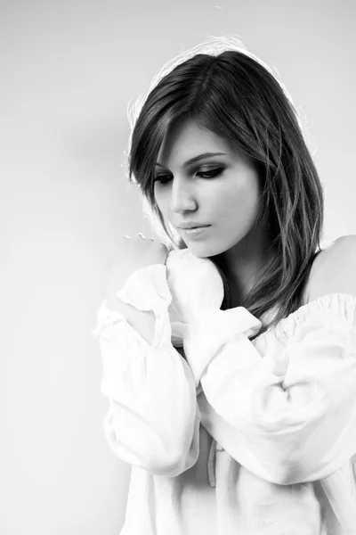Black and white photo of beautiful caucasian girl wearing a white blouse with light grey background — Stock Photo, Image