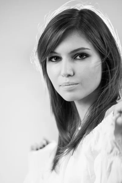 Foto en blanco y negro de una hermosa chica caucásica con una blusa blanca con fondo gris claro — Foto de Stock