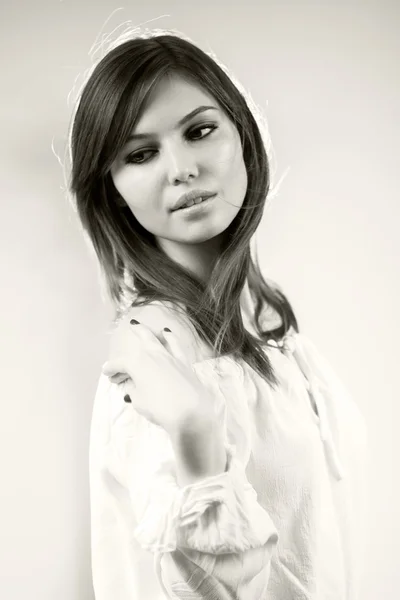 Black and white photo of beautiful caucasian girl wearing a white blouse with light grey background — Stock Photo, Image