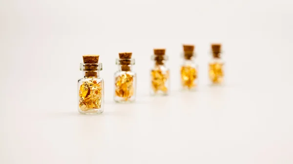 Still life sammansättning med små glasflaskor med gyllene papper — Stockfoto