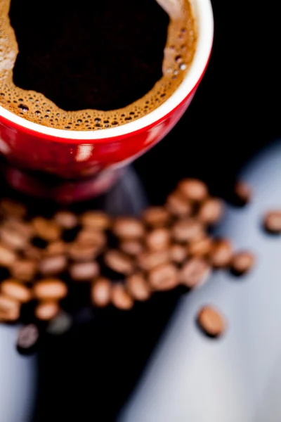 Красная чашка кофе с кофейными зёрнами — стоковое фото