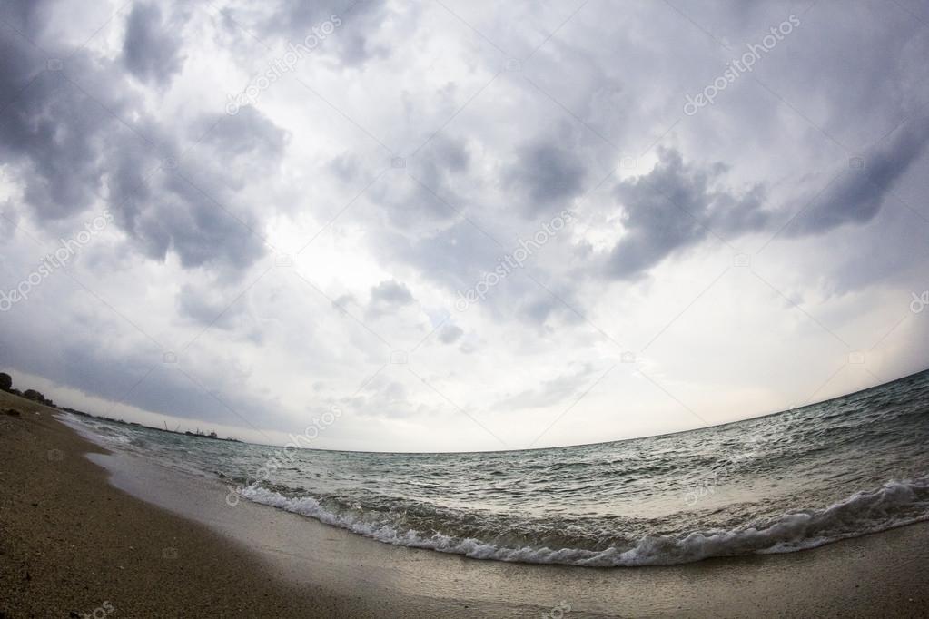 Aegean sea, beach and sky with clouds before the storm. Fish eye lens effect