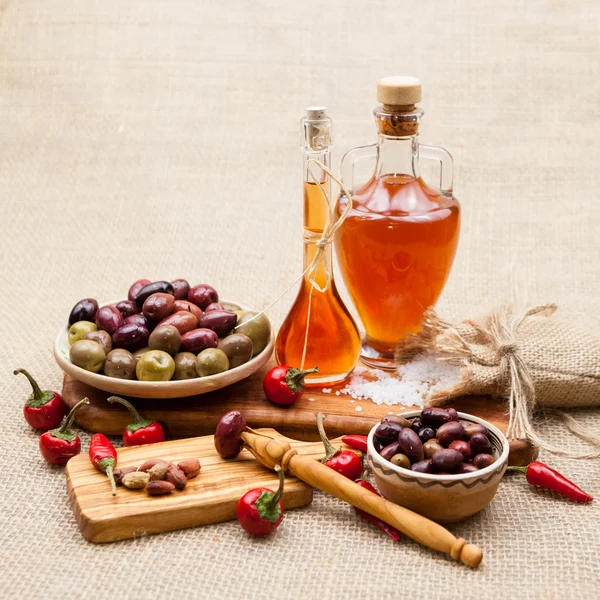 Composition with olive wood, olives, vinegar and spices with burlap texture in the background