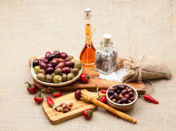 Composition with olive wood, olives, vinegar and spices with burlap texture in the background