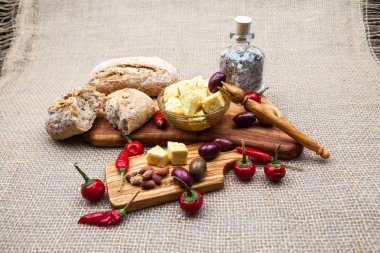 Zeytin ahşap, zeytin, zeytinyağı, ekmek ve baharat peynir taşlarla çuval bezi doku içinde belgili tanımlık geçmiş ile kompozisyon