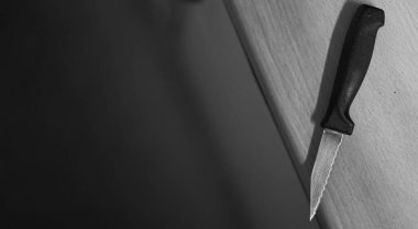 Mutfak masasının üzerinde siyah-beyaz siyah siyah renkli atmosfer bıçağı var. Yüksek kontrastlı ve sahnelemeli.