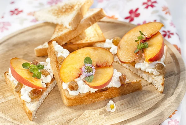 Toast with cottage cheese, raisins and fresh ripe peaches — Stock Photo, Image