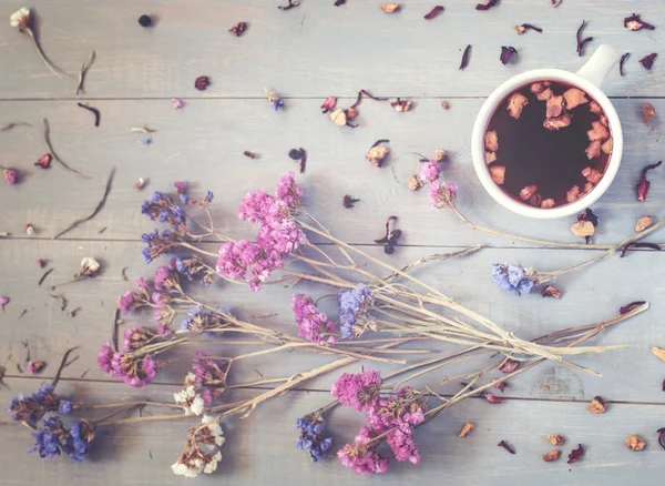 A cup of tea with flowers and tea around it — Stock Photo, Image