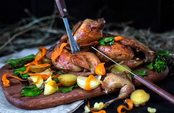 Codornices asadas con verduras en una tabla de madera Fotos De Stock