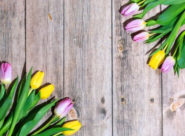 Ahşap bir masada laleler olan bir Paskalya kartpostalı.