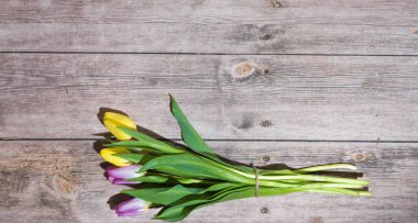 Ahşap bir masada laleler olan bir Paskalya kartpostalı.