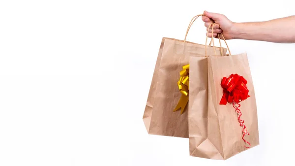배너. 코로나 바이러스가 유행하는 동안 무선으로 크리스마스 선물을 멀리서 안전하게 배달하는 거죠. 닫아. 배달원 한 명이 흰 바탕에 활을 단 종이 선물 가방을 들고 있다. 복사 공간. — 스톡 사진