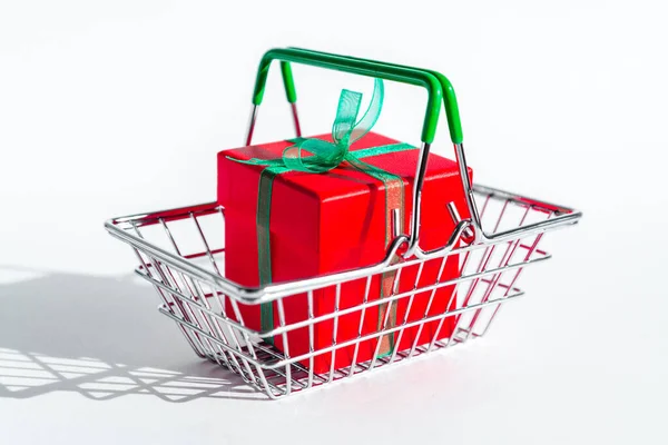 白い隔離された背景に赤いギフトボックス付きの小さな食料品バスケット 創造的なクリスマスのショッピングオンライン 年末年始およびブラックフライデーの休日の販売および割引 商売だ 固い影 — ストック写真