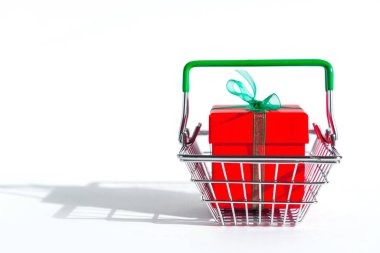 Beyaz izole edilmiş arka planda kırmızı hediye kutusu olan market sepeti. İnternetten Noel alışverişi. Uzayı kopyala Yılbaşı ve Kara Cuma 'da tatil satışları ve indirimler. Ticaret işi. Metin için boşluk.