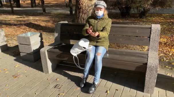 Caucasian Woman Protective Mask Sits Bench Empty Autumn Park Treats — Stock Video