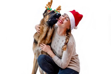 Pankart. Geyik boynuzlu köpek Noel Baba şapkalı kızı öpüyor. Kadınlar ve evcil hayvanlar yeni yılı, Noel 'i kutlar. Beyaz arka planda Alman çoban köpeği yazılı tebrik kartı. Boşluğu kopyala