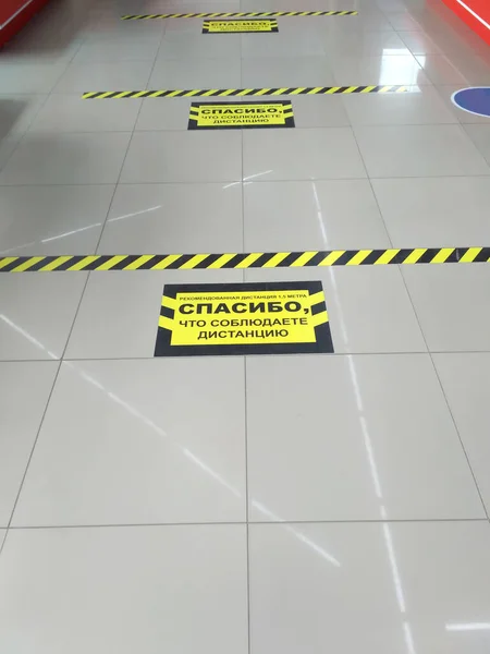 Empty store. Secure line marking on floor for waiting in line at a safe distance with Russian text: recommended social distance is 1.5 meters, thank you for keeping distance. Coronavirus pandemics. — Stock Photo, Image