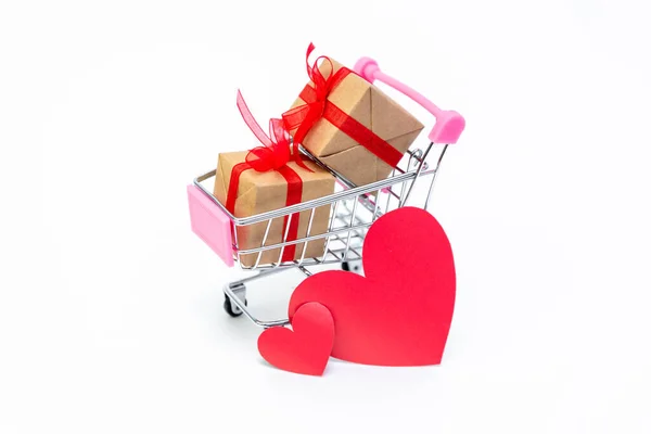 Malý nákupní vozík s dárkovými krabicemi na bílém pozadí. Dát dárky s láskou na Valentýna, Vánoce a narozeniny. Nakupování online. Dovolenkový prodej a slevy. Maloobchodní a velkoobchodní nákupy. — Stock fotografie