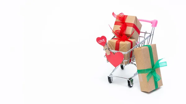 Kleine boodschappenkarretje met geschenkdoosjes op witte achtergrond. Geef geschenken met liefde op Valentijnsdag, Kerstmis en verjaardag. Online winkelen. Vakantie verkoop en kortingen. Kleinhandel en groothandel. — Stockfoto