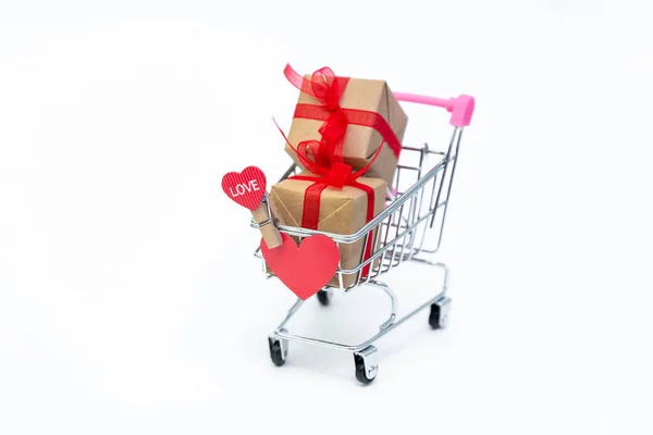 Piccolo carrello della spesa con scatole regalo su sfondo bianco. Regala con amore il giorno di San Valentino, Natale e compleanno. Shopping online. Saldi vacanze e sconti. Acquisti al dettaglio e all'ingrosso. — Foto Stock