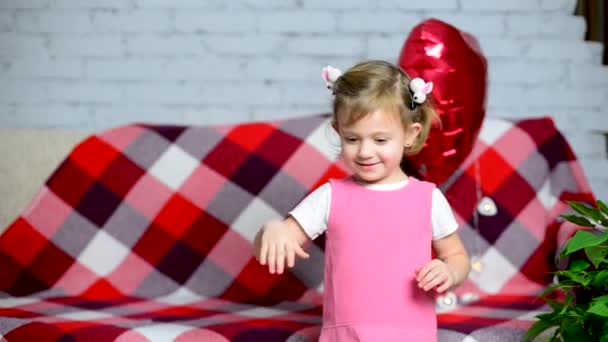 Menina bonita brincando com um balão rosa na forma de um coração. Dia dos Namorados. As crianças adoram. Criança feliz celebra aniversário, parabeniza pelo Dia das Mulheres e Dia das Mães. — Vídeo de Stock