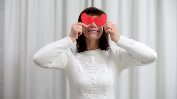 Gekke volwassen senior vieren Valentijnsdag. Vrouw bedek ogen met rode Valentijnskaarten en glimlach. Romantische relaties, liefde en daten met pensioen. Levensstijl van ouderen. — Stockvideo