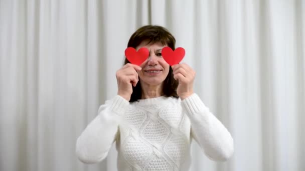 Galna vuxna seniorer firar Alla hjärtans dag. Kvinna täcka ögon med röda valentin kort och leende. Romantiska relationer, kärlek och dejting i pension. Äldre människors livsstil. — Stockvideo