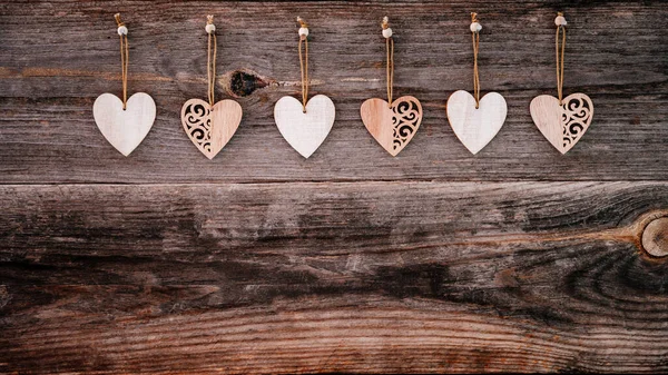 Valentijnsdag achtergrond. Bruine oude natuurlijke planken in grunge stijl met houten decoratieve hartjes. Begrepen, ruimte. Bovenaanzicht. Oppervlakte van de tafel om plat te schieten. Concept liefde, romantische relatie. Banner. — Stockfoto