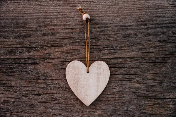 バレンタインデーの背景。1つの木製の装飾的な心を持つグランジスタイルの茶色の自然板。最上階だ。テーブルの表面にフラットレイアウトを撮影します。愛の概念、恋愛関係. ストックフォト