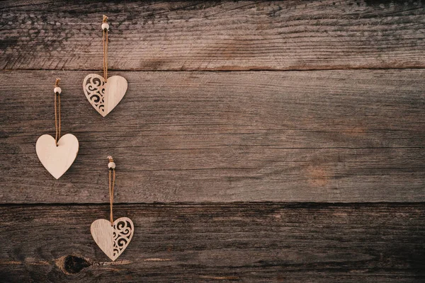 Valentijnsdag achtergrond. Bruine natuurlijke planken in grunge stijl met drie houten decoratieve harten. Begrepen, ruimte. Bovenaanzicht. Oppervlakte van de tafel om plat te schieten. Concept liefde, romantische relatie. — Stockfoto