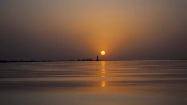 Hermoso paisaje escénico. Atardecer dorado en el mar. Plena calma, superficie tranquila de agua en el océano con vistas al faro. Reflejo del sol anaranjado del amanecer sobre las olas. Copiar espacio. — Vídeos de Stock