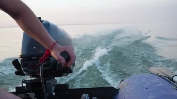 L'homme en gilet de sauvetage conduit un bateau pneumatique en caoutchouc motorisé. Gros plan de la main et du moteur. Planifier. Des vagues sur l'eau. Excursion en bateau à grande vitesse. Le concept de liberté et de circulation. Voyage de pêche. — Video