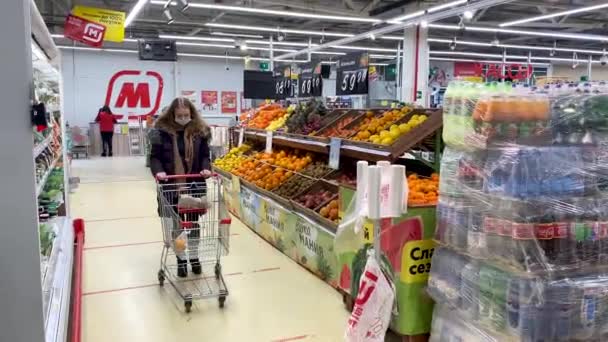 Una donna adulta in maschera protettiva con un carrello compra cibo al supermercato Magnet durante l'epidemia di pandemia di coronavirus. Misure di protezione e prevenzione. Russia, Volgodonsk: 21 febbraio 2021. — Video Stock