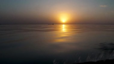 Motorlu bir teknede yüksek hızda su üstünde altın gün batımı. Güzel manzara manzarası. Dalgaların üzerinde turuncu şafak güneşinin yansıması. Titriyor ve atıyor. Akşam balığından dönerken.