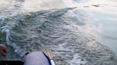 Adam motorlu lastik şişirilebilir tekne kullanıyor. El ve motora yakın çekim. Planlama. Suda dalgalar. Yüksek hızda tekne gezisi. Özgürlük ve hareket kavramı. Balık tutma gezisi.