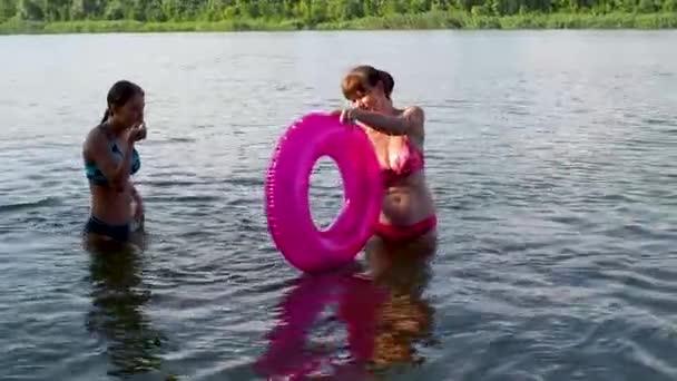 Glückliche Mädchen und Frauen spielen im Sommer im Wasser am Strand. Teenager-Tochter springt in einen aufblasbaren Kreis und schwimmt durch ihn. Wochenenden und Schulferien. Urlaubskonzept, Spaß und Menschen. — Stockvideo