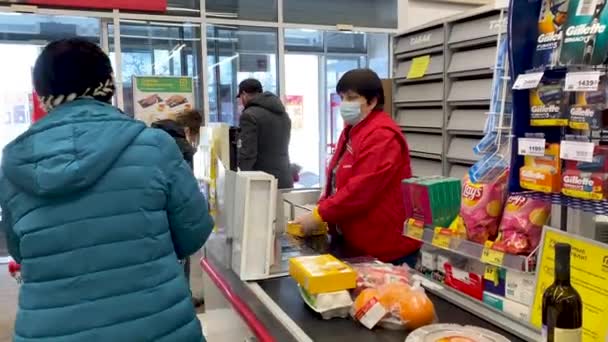 Žena pokladní v ochranné masce a rukavice prodává jídlo v supermarketu na pokladně. Ochrana prodávajícího a kupujícího během karantény a pandemického koronaviru. Rusko, Volgodonsk února 24, 2021. — Stock video