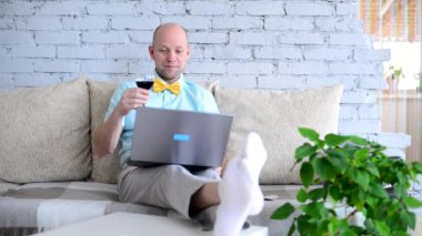 Sanal tatil. Online randevuda, tişörtlü ve papyonlu şık bir adam ve bir bardak şarap. Mutlu adam tost diyor ve tatilini uzaktan izole bir şekilde görüntülü sohbet ederek kutluyor. Kilit altında aşk.