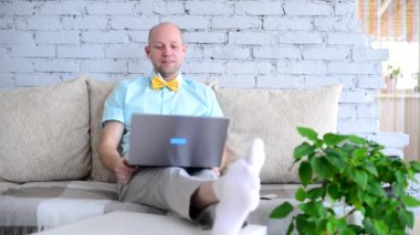 Sanal tatil. Online randevuda tişörtlü ve papyonlu şık erkek blogcu. Mutlu insan mutlu bir şekilde konuşur, güler ve güler bir görüntülü sohbet sırasında kendini izole eder. Yalnızken aşk.