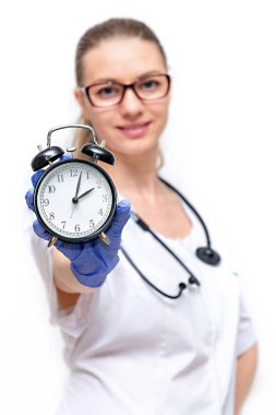 Beyaz önlüklü kadın doktor elinde nöbet tutuyor. Sağlığınla ilgilenme zamanı. Beyaz arka planda izole edilmiş. Doktora zamanında erişim, tıbbi muayeneleri geçme, hastalıkların önlenmesi.