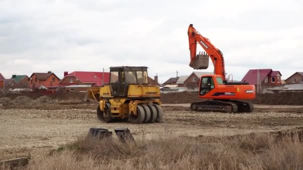 Průzkumník, buldozer a válečkové práce na staveništi. Stroje provádějí výkopové práce. Těžba půdy a sutin pro obytné budovy. Volgodonsk, Rusko 10. března 2020. — Stock video