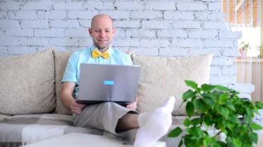 Sanal tatil. Online randevuda tişörtlü ve papyonlu şık erkek blogcu. Mutlu insan mutlu bir şekilde konuşur, güler ve güler bir görüntülü sohbet sırasında kendini izole eder. Yalnızken aşk.